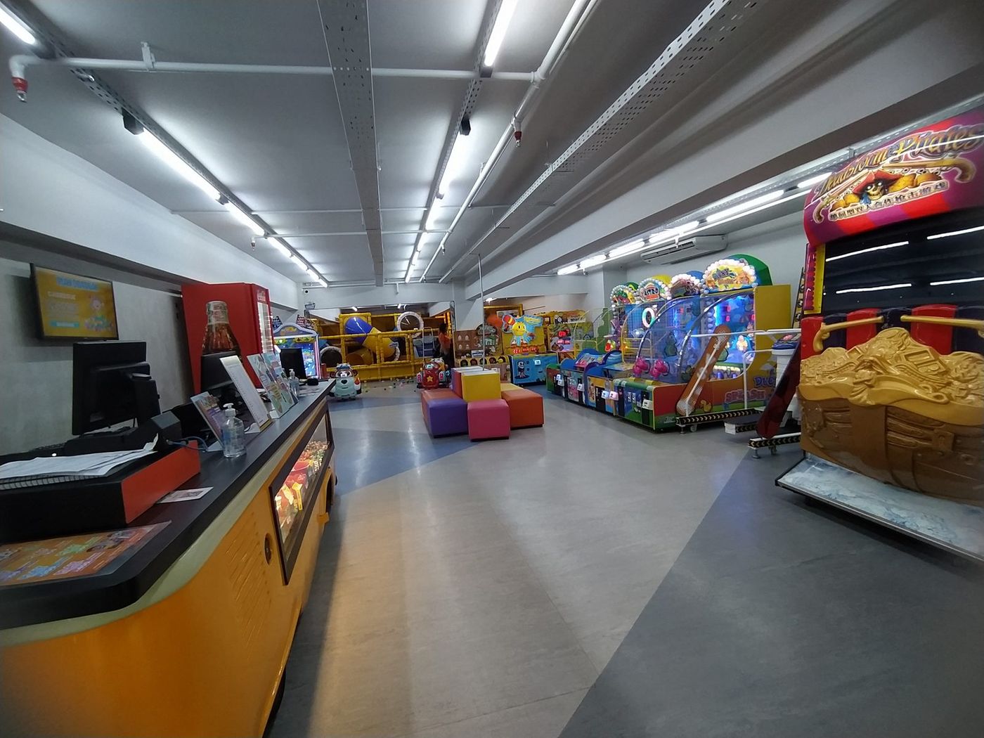 Parque coberto do Play Games Águas Claras com brinquedos e máquinas iluminadas