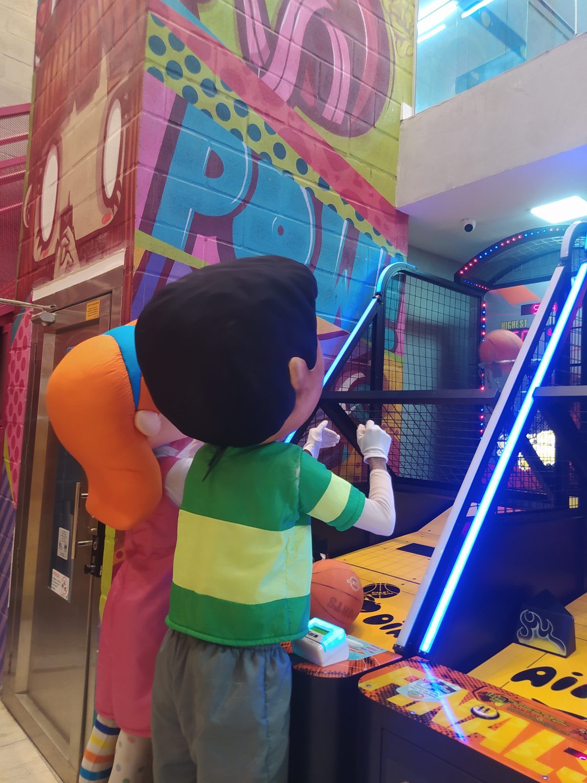 Mascote do Play Games jogando em uma máquina do parque