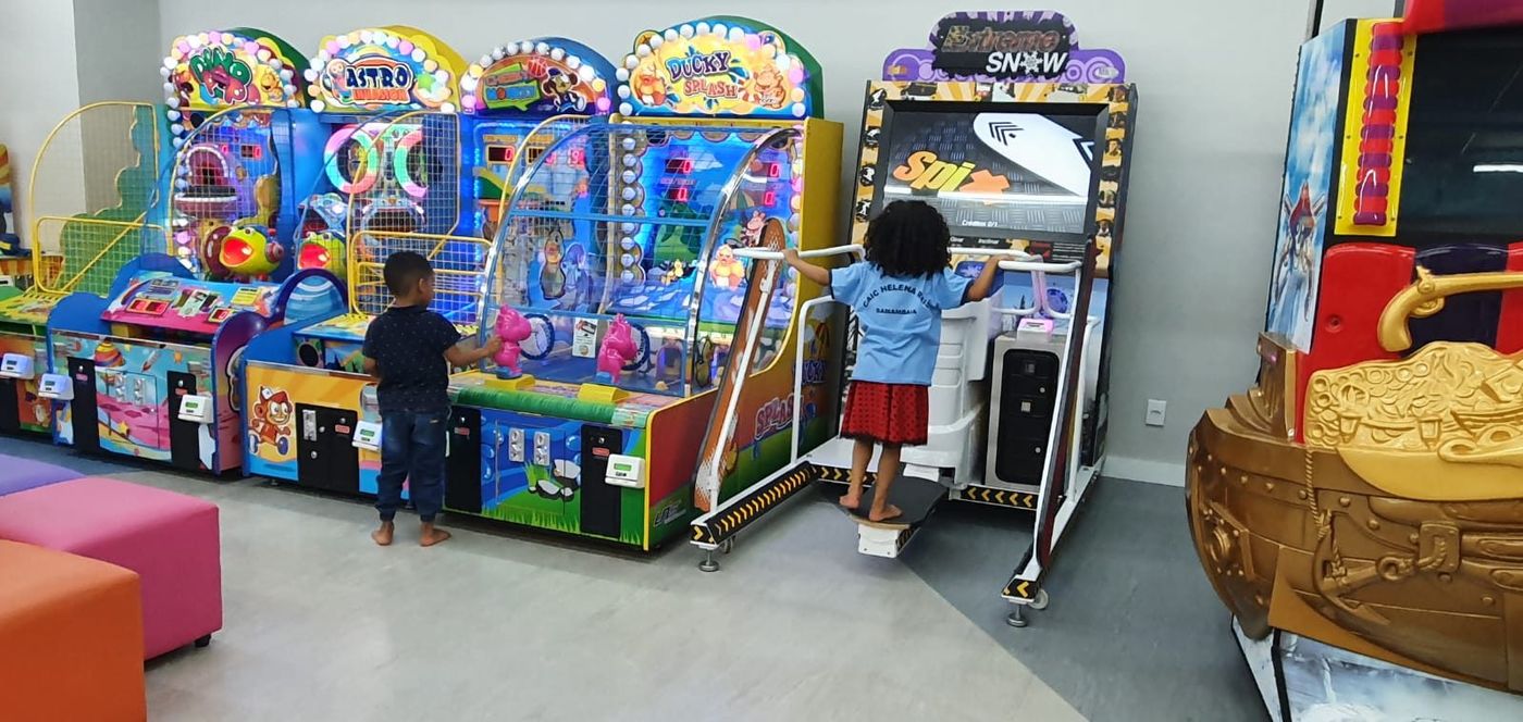 Crianças de uniforme brincando nas máquinas do parque